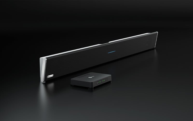 A Nureva HDL310 audio conferencing system on a dark background, comprising a black horizontal microphone and speaker bar and a rectangular compact connect module.