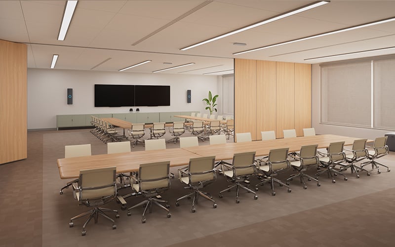 Large divisible room with conference tables, chairs and a room divider, equipped with a Nureva HDX audio system for clear hybrid meeting audio. Two black vertical audio bars are mounted on the wall, either side of a display. Two white microphone pods are mounted on the ceiling.