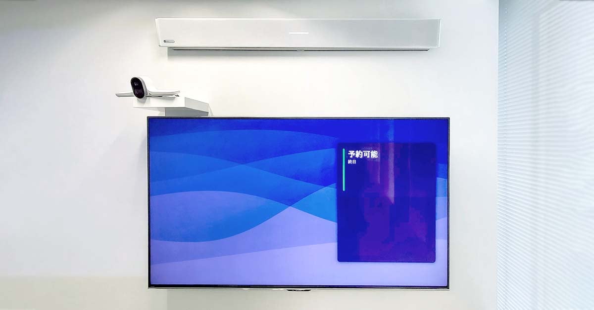 A close-up of a wall-mounted display with a video conferencing camera and a white Nureva HDL310 audio system mounted above the screen.