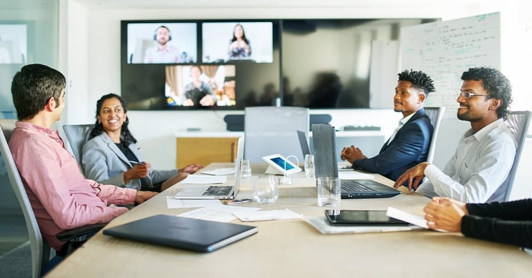 Team members in the office meet with remote participants in a hybrid work environment