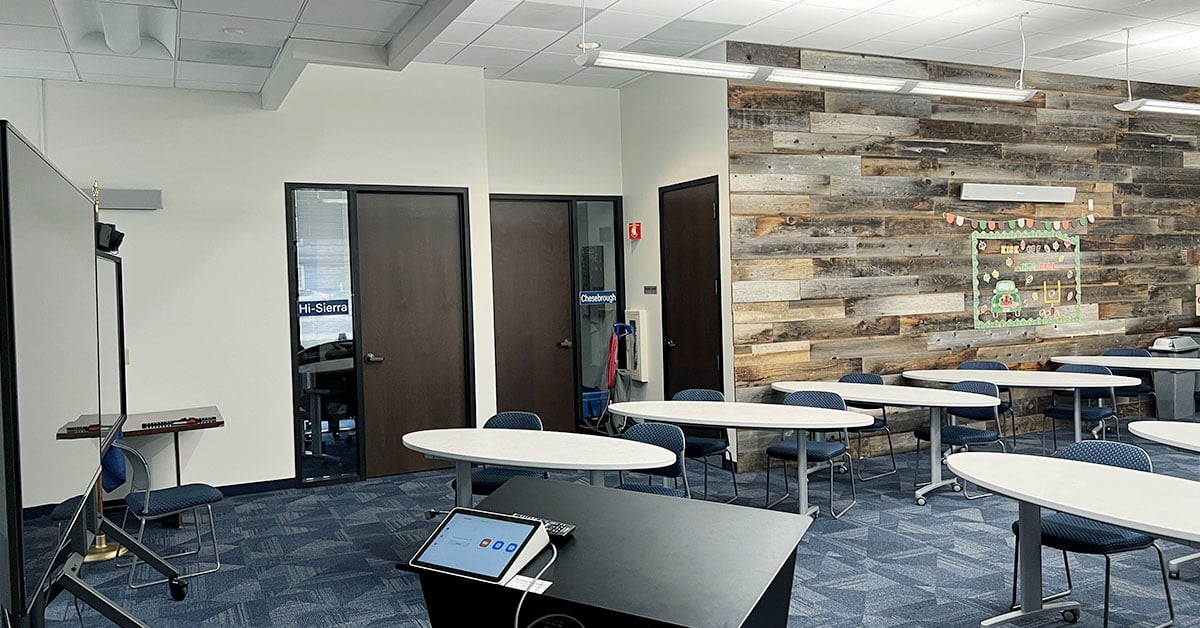 A multipurpose room with several tables and chairs, a podium, a display and a Nureva HDL410 audio conferencing system