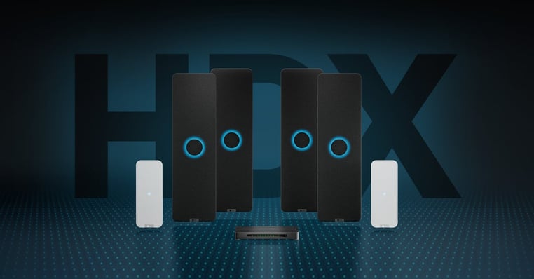 A Nureva HDX system with a configuration comprising a system hub, two audio bars and two microphone pods. In the background are the large capital letters HDX and in the foreground are blue dots representing Microphone Mist technology. 