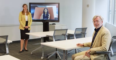 Three people demonstrate Voice Amplification Mode in a room and remote