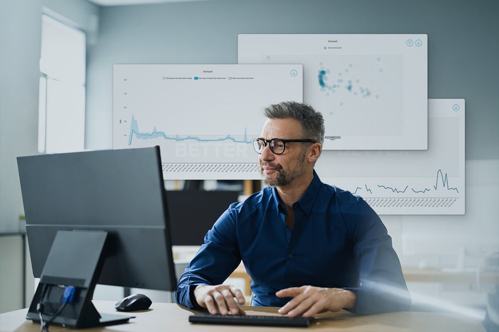 IT professional working at a desktop computer with overlaid room analytics charts indicating the Nureva Console data that can be paired with Microsoft Power BI.
