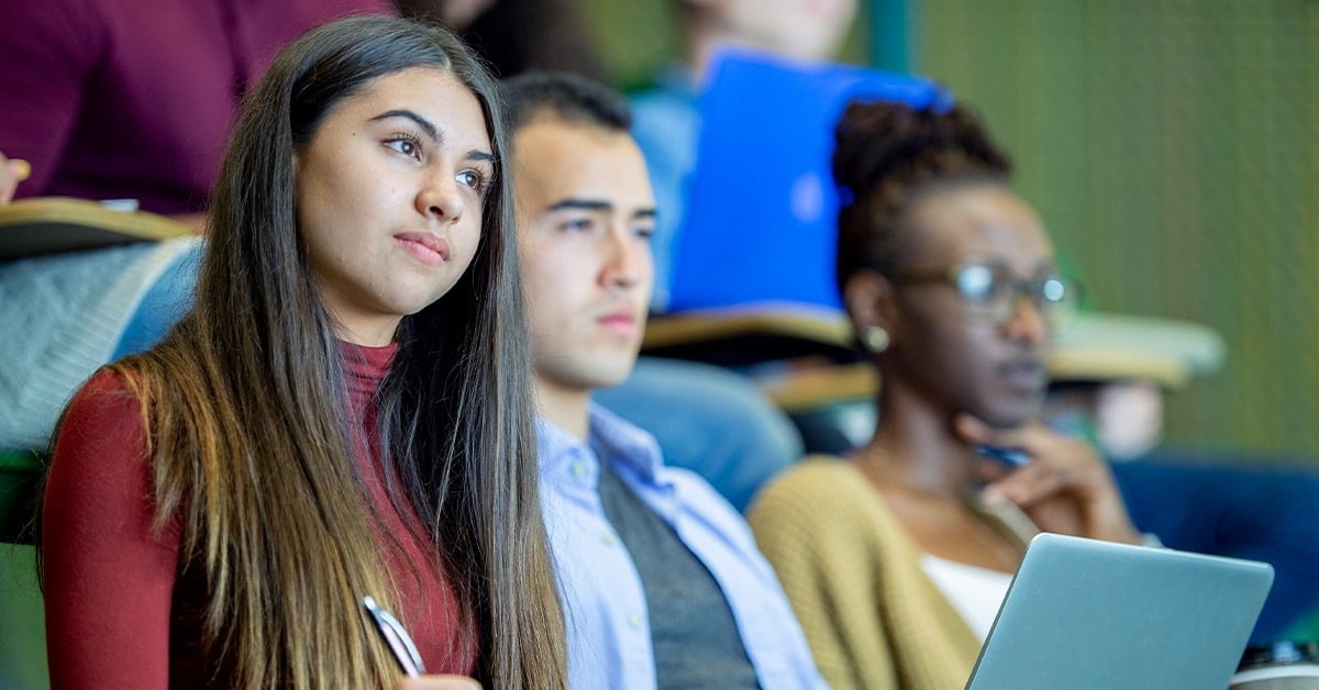 University students attentively listening during a lecture in a tiered classroom, representing Athens State University's adoption of Nureva audio for hybrid learning.