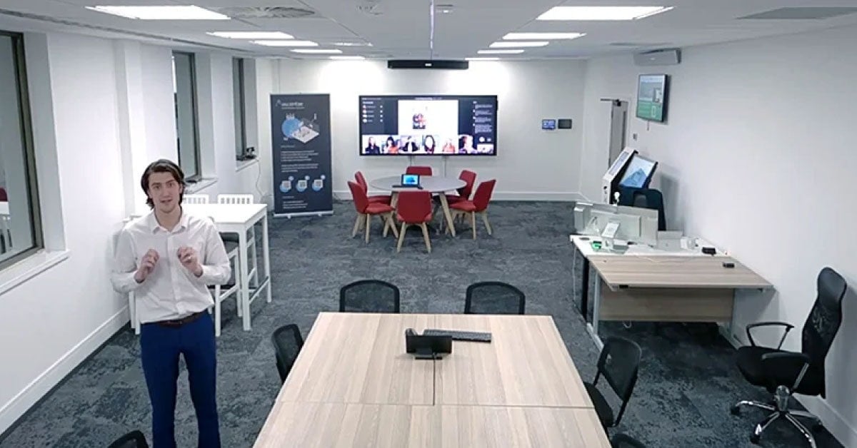 Presenter standing in a University of Chester demonstration room equipped with a Nureva audio system, dual displays and flexible seating for hybrid learning showcases.