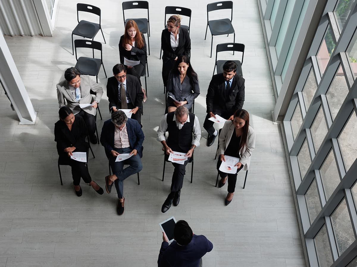 Overhead view of government employees attending a training session in a bright open space with a presenter and printed materials.