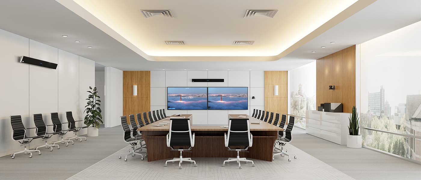 Spacious executive boardroom with chairs around a dark wood table and dual widescreen displays, with a Nureva 410 audio conferencing system mounted on the walls.