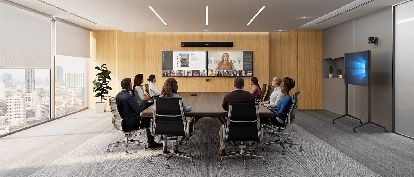 Large Microsoft Teams meeting room featuring a Microsoft-certified Nureva HDL310 audio conferencing system mounted above dual displays running a Teams Rooms call, with diverse in-person participants seated around a dark wood conference table and remote attendees visible in gallery view on screen.