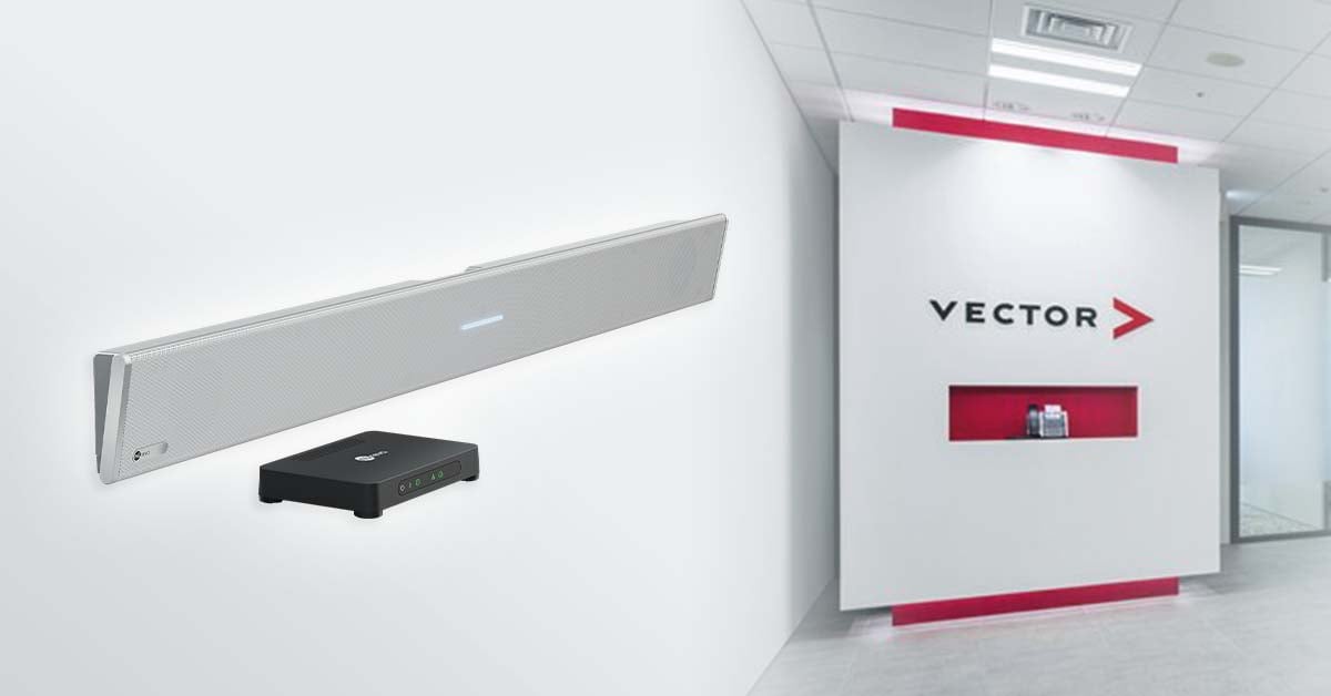 A white Nureva HDL310 microphone and speaker bar shown on a white wall beside its black connect module. In the background, a modern office entrance displays the Vector Japan logo on a white and red feature wall.