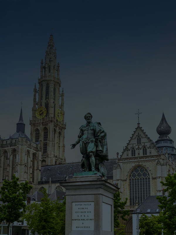 Bronze statue of Peter Paul Rubens on a stone pedestal in the Groenplaats square, with the Gothic spire of the Cathedral of Our Lady towering in the background, Antwerp, Belgium.