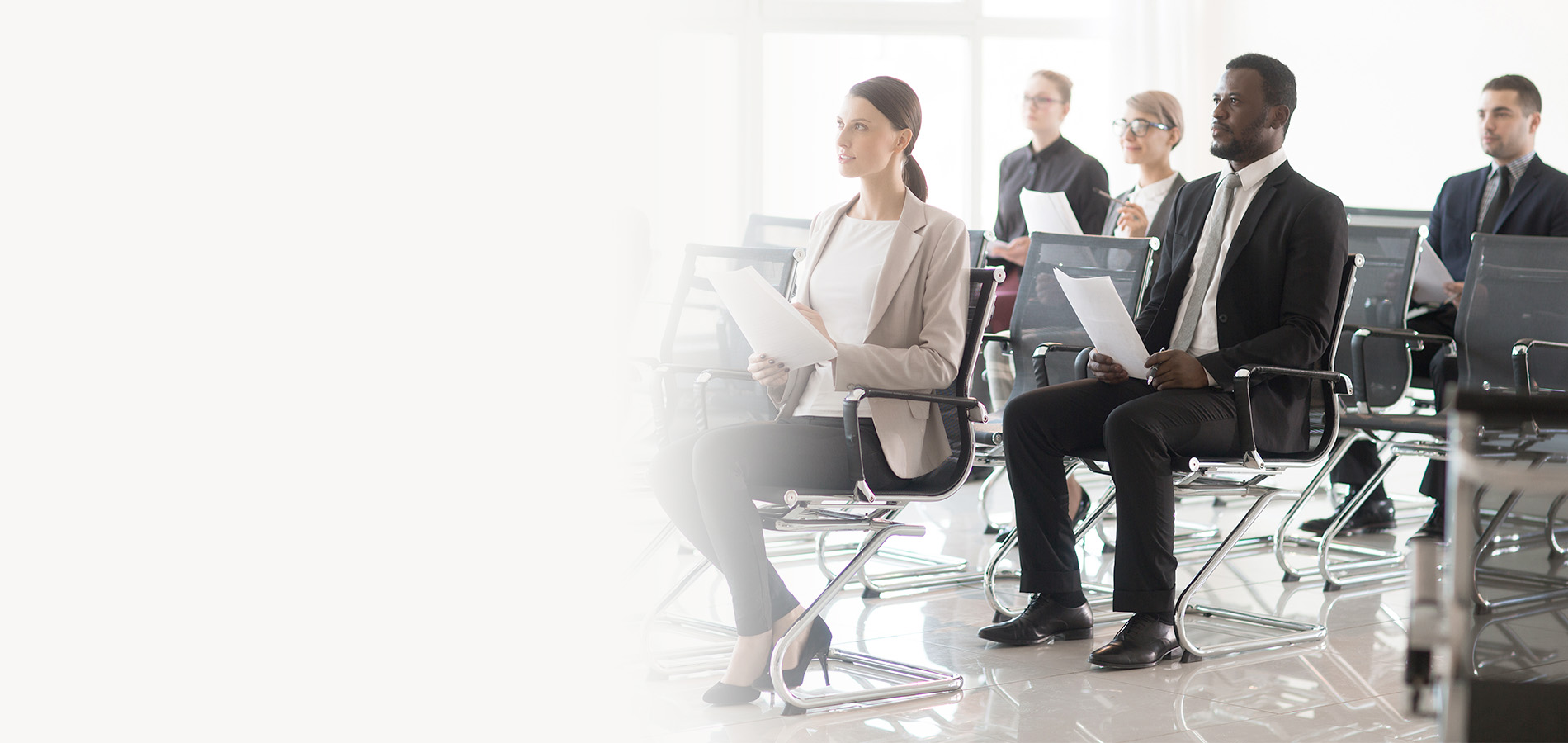 Government professionals seated in a bright training room holding documents and listening attentively during a public sector learning session.