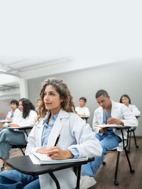 Medical students in white coats seated at desks attentively listening during a healthcare education session supported by Nureva audio solutions.