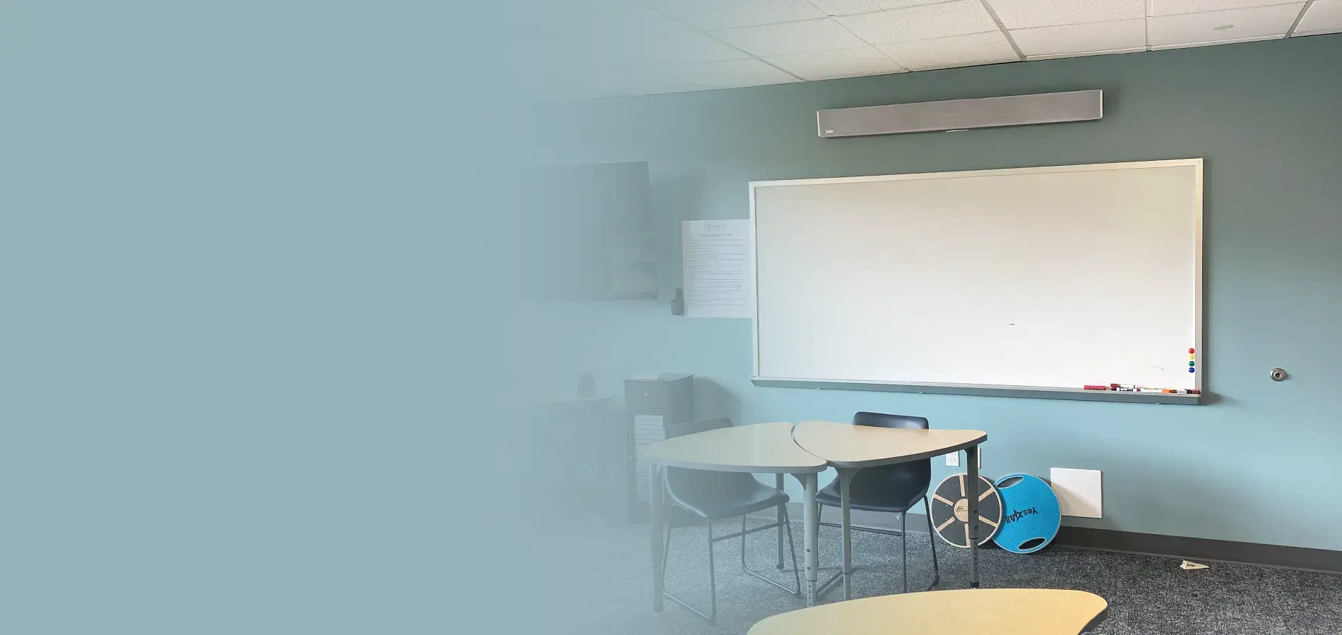 Wide-format view of a Thira Health therapy room with a Nureva HDL audio bar mounted above a whiteboard, supporting remote mental health sessions.
